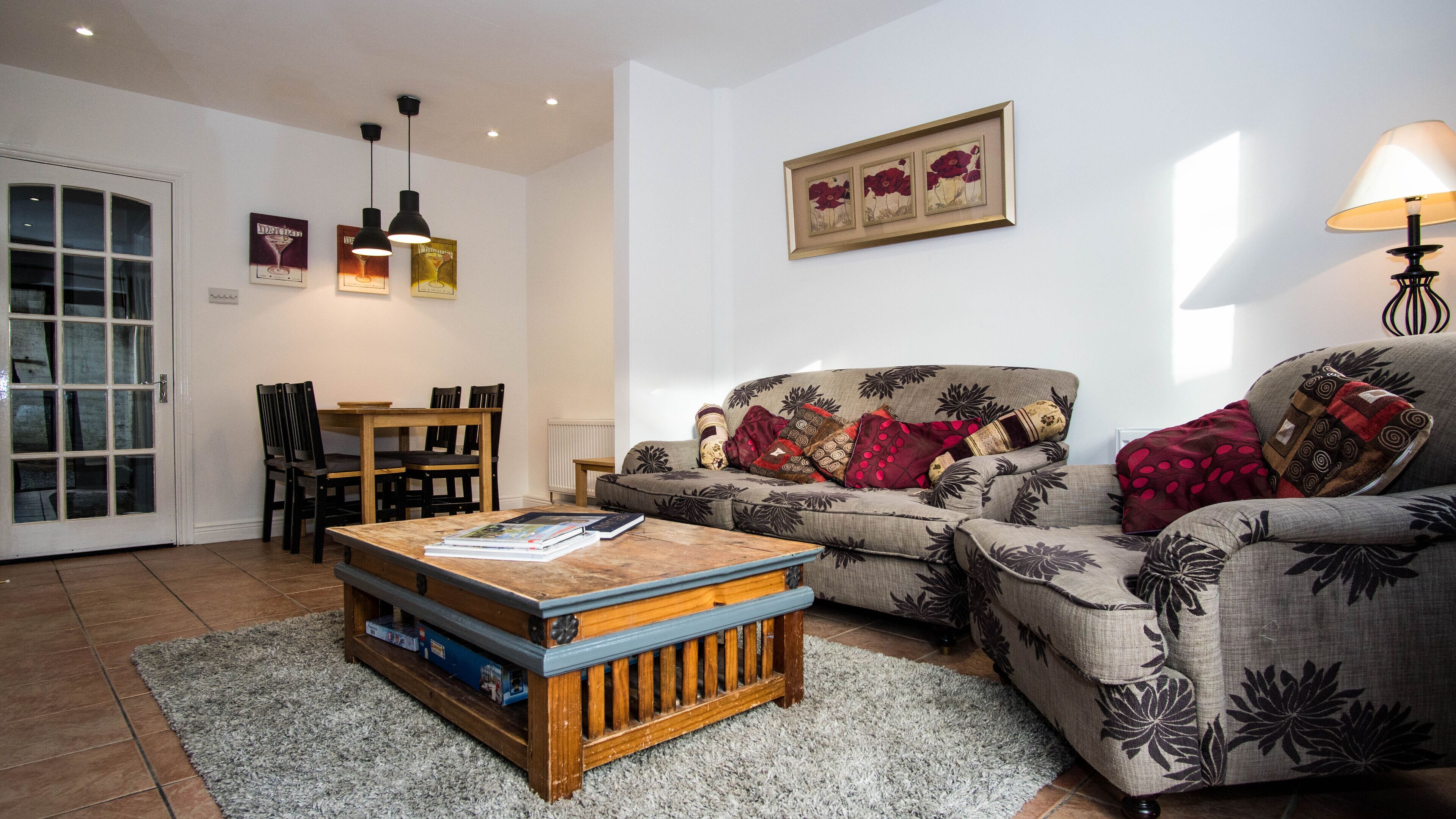 A living room with a sofa, a coffee table, a dining table with chairs, and a framed picture on the wall.