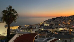 Una cittadina costiera al crepuscolo, con edifici e una palma.