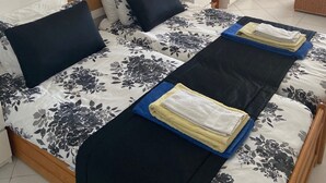 Una camera d'albergo con un letto grande, un comodino, una lampada, una cassettiera e uno specchio.