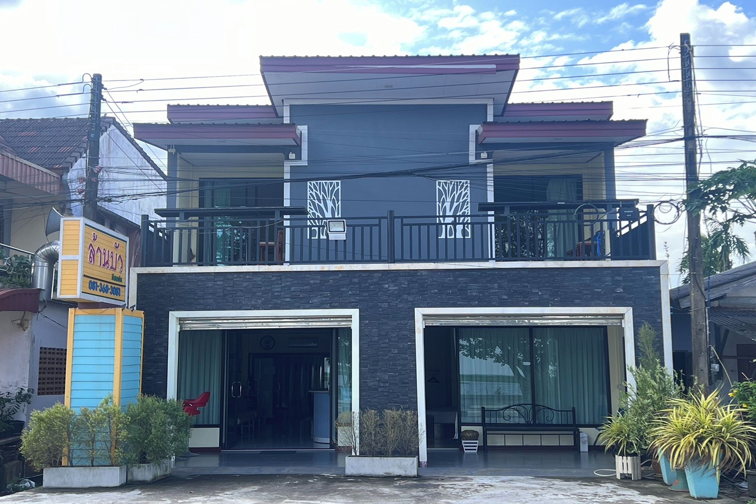 Un edificio de dos pisos con un balcón, ventanas amplias y un cartel.