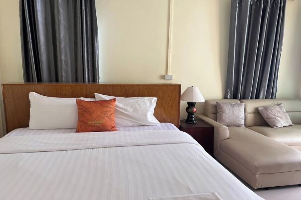 Ein Hotelzimmer mit Bett, Nachttisch, Lampe und Sofa.
