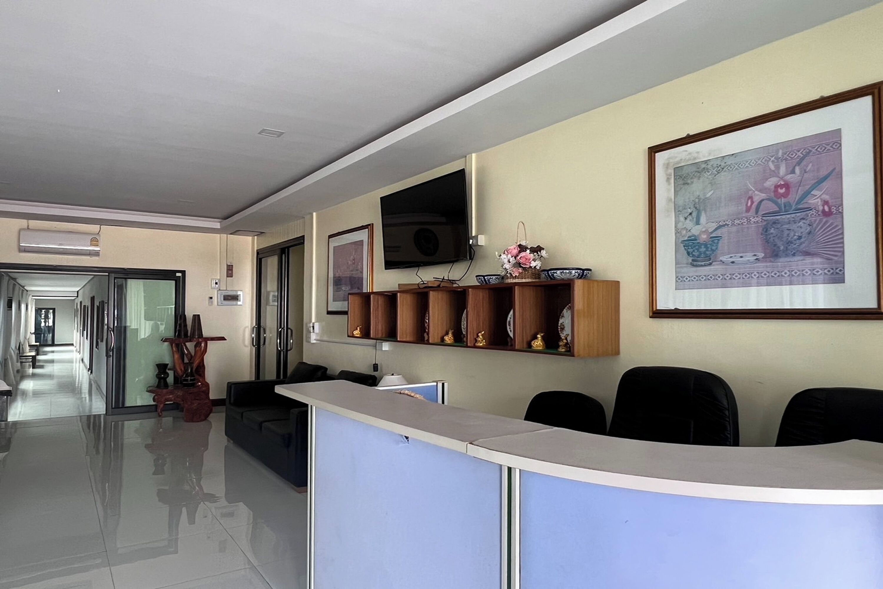 Zona de recepción con mostrador, asientos, televisor y una obra de arte enmarcada en la pared.