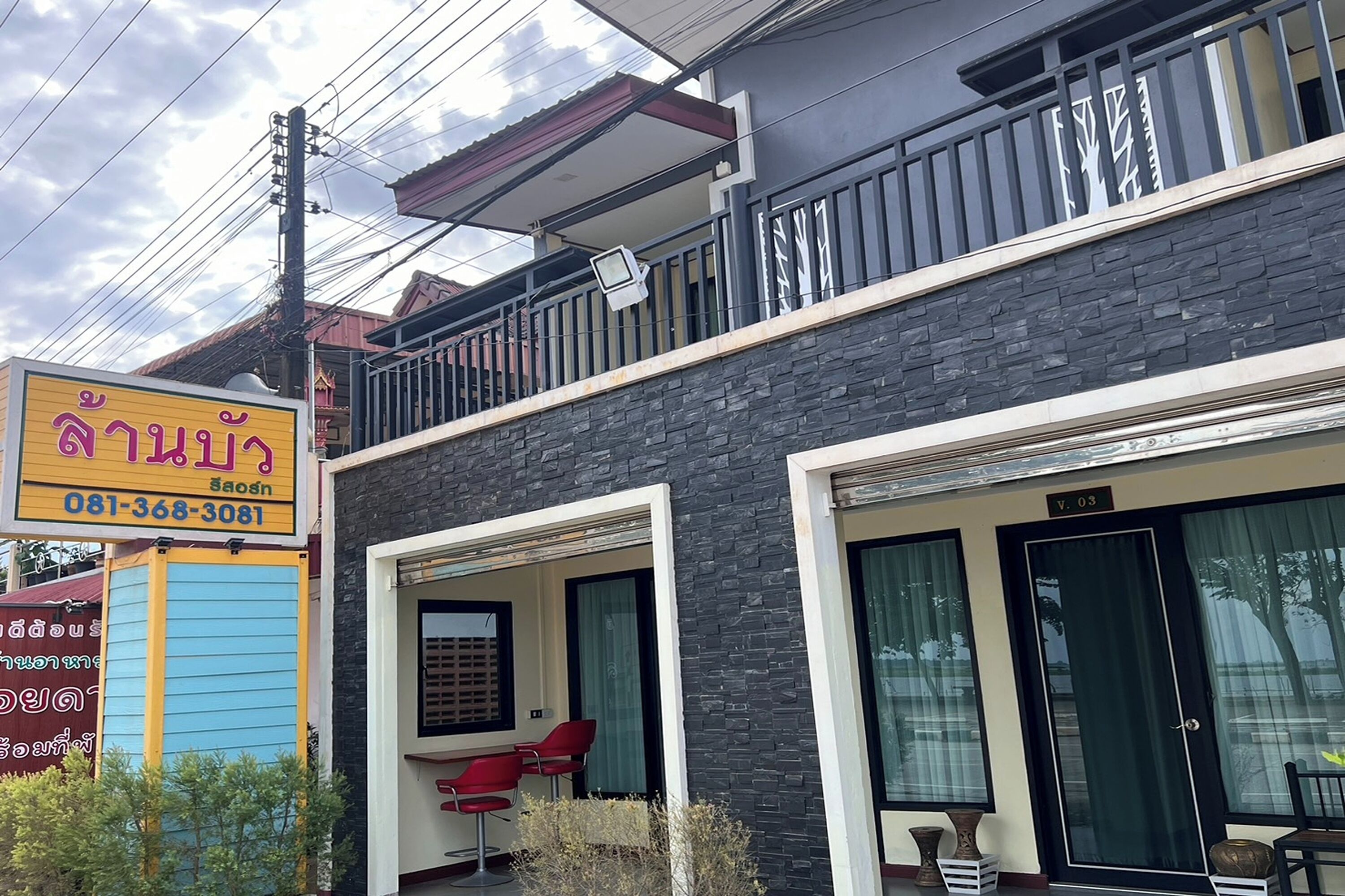 A building with a balcony, a signboard, and a door.