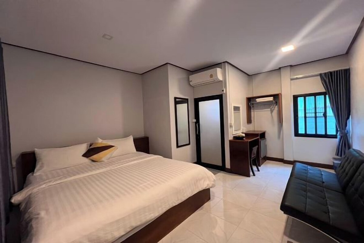 A modern hotel room with a large bed, a desk, and a sofa.