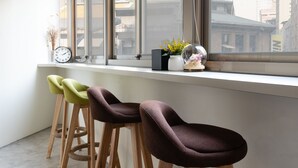 A modern interior with a window view of a cityscape, a clock, and a bar area with stools. - 109 Hostel Taipei (Taipei)