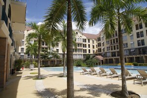 Un hotel con piscina, palme e poltrone relax.