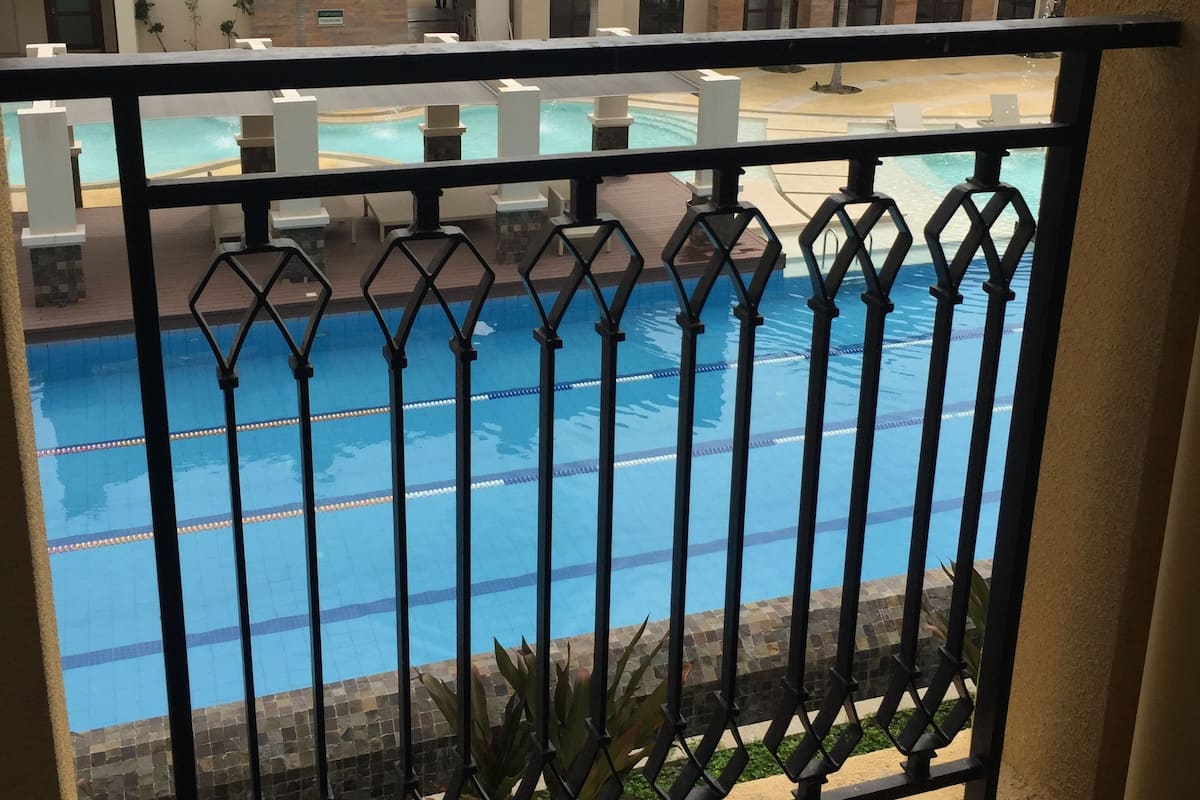 A pool area with a view of a building with multiple balconies and a tiled roof.