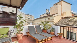 Una terraza en la azotea con dos sillones de descanso, una mesita y plantas en macetas.