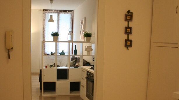 A kitchen with a white cabinet, a stove, and a window with curtains. - Casa Palladio, in the heart of the historic center  (Vicenza)