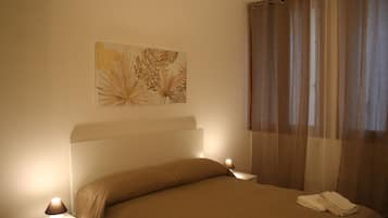 A neatly made bed with a headboard, two bedside lamps, and a wall-mounted artwork.