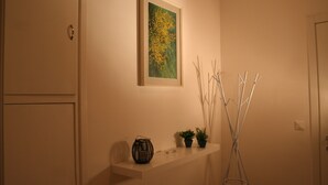 A hallway with a framed painting, a shelf with decorative items, and a tall floor lamp. - Casa Palladio, in the heart of the historic center  (Vicenza)