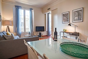 Ein modernes Wohnzimmer mit Sofa, Fernseher, Esstisch und einer grünen Dekoteller.