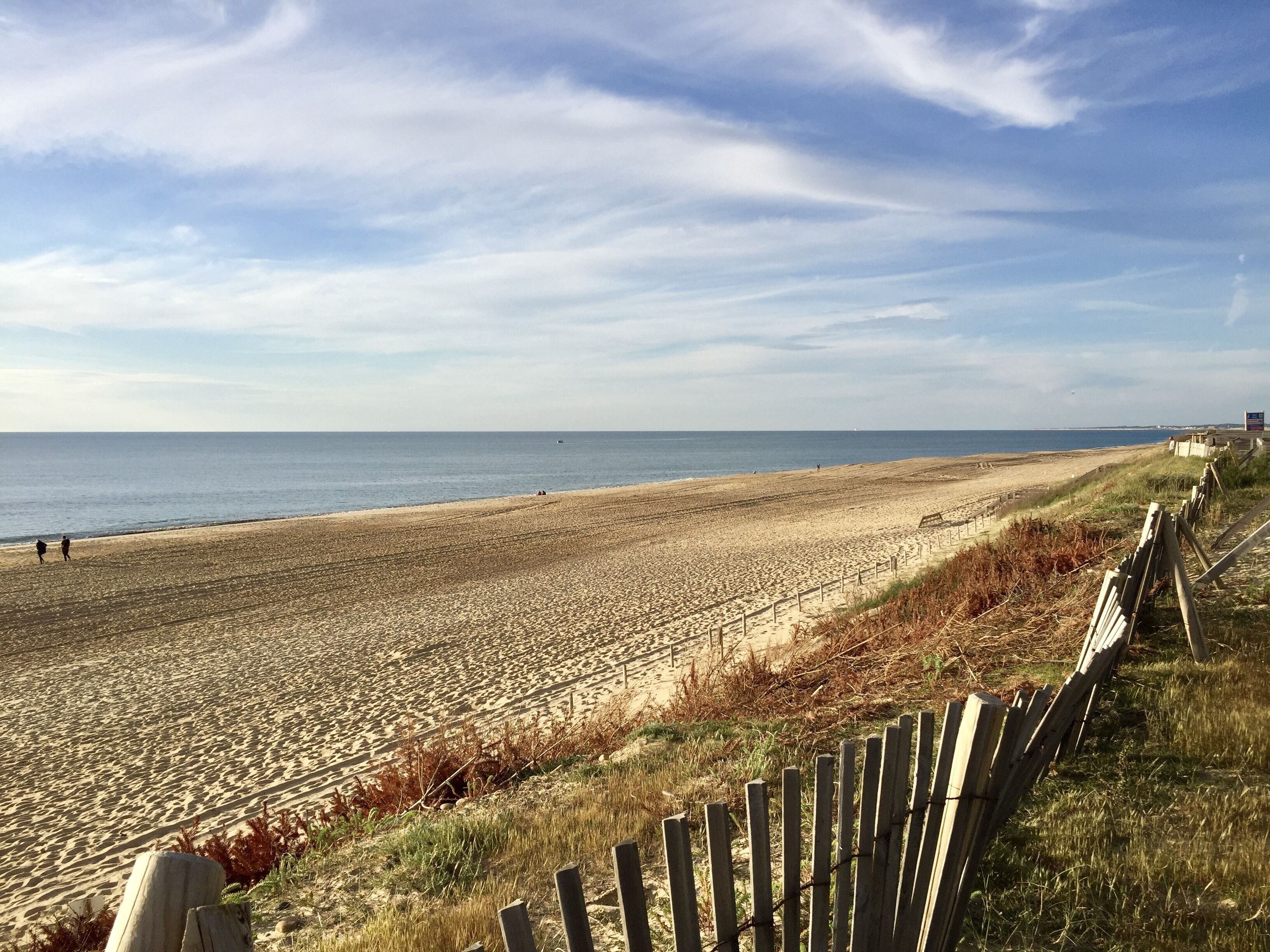 A beach with a wooden fence and a clear sky.