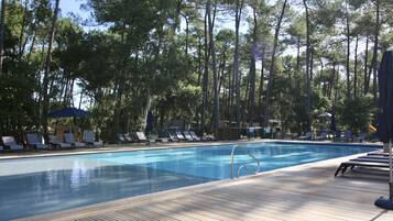 Een buitenzwembad, parasols bij het zwembad en ligstoelen