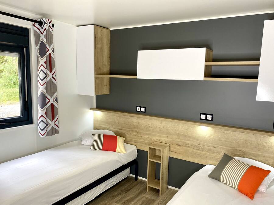 A compact room with two beds, a window, and built-in shelves.