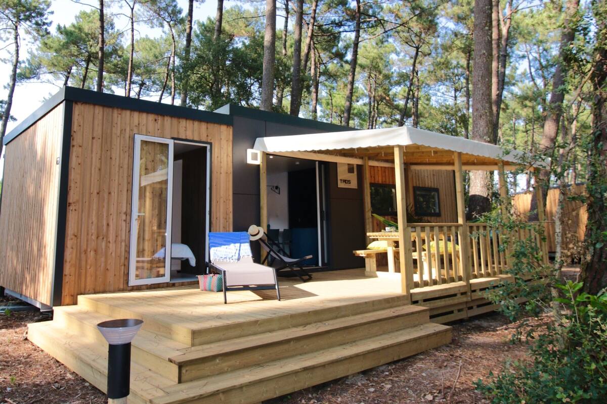 A wooden cabin with a porch, a chair, and a table.