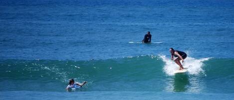 Three surfers on the water with a clear view of the ocean and a distant horizon.