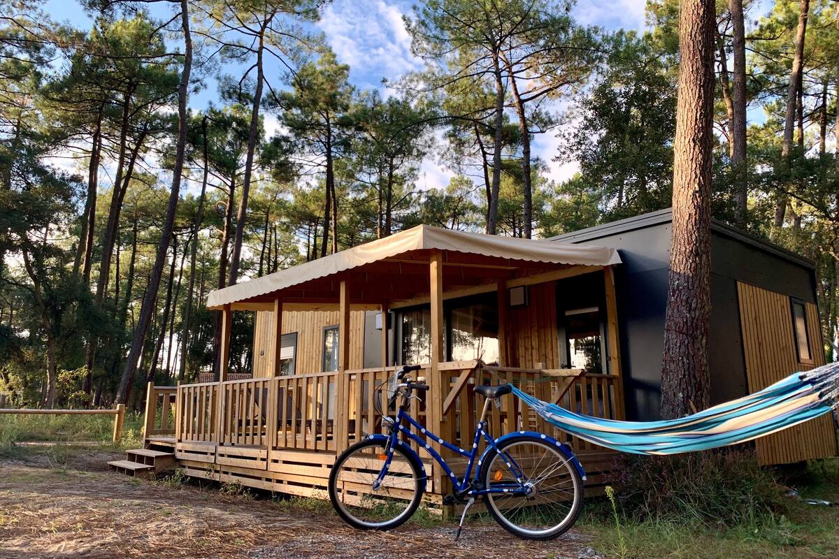 A wooden cabin with a porch, a hammock, and a bicycle.