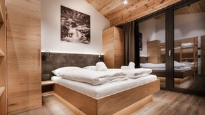 Une chambre moderne avec un lit en bois, une tête de lit, une lampe fixée au mur et une grande fenêtre.
