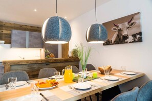 Enjoy meals in this stylish dining area with a long table, pendant lights, and a beautiful artwork above.