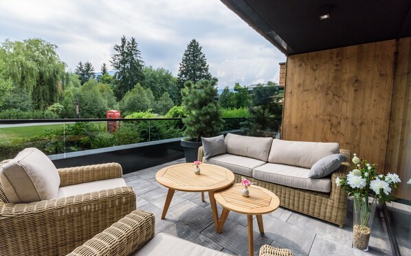 Une terrasse extérieure aménagée avec des meubles en osier, un canapé et deux tables rondes.
