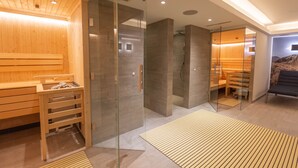 A modern sauna with glass walls, wooden benches, and a separate relaxation area with a sofa. - SR, Top 5 - Ap. 86m² mit 2 SZ, Terrasse 37 m² (Zell am See)