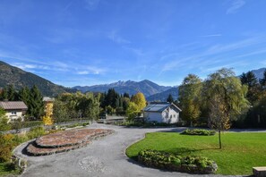 A rural setting with a paved area, a grassy field, and a building with a sloped roof.