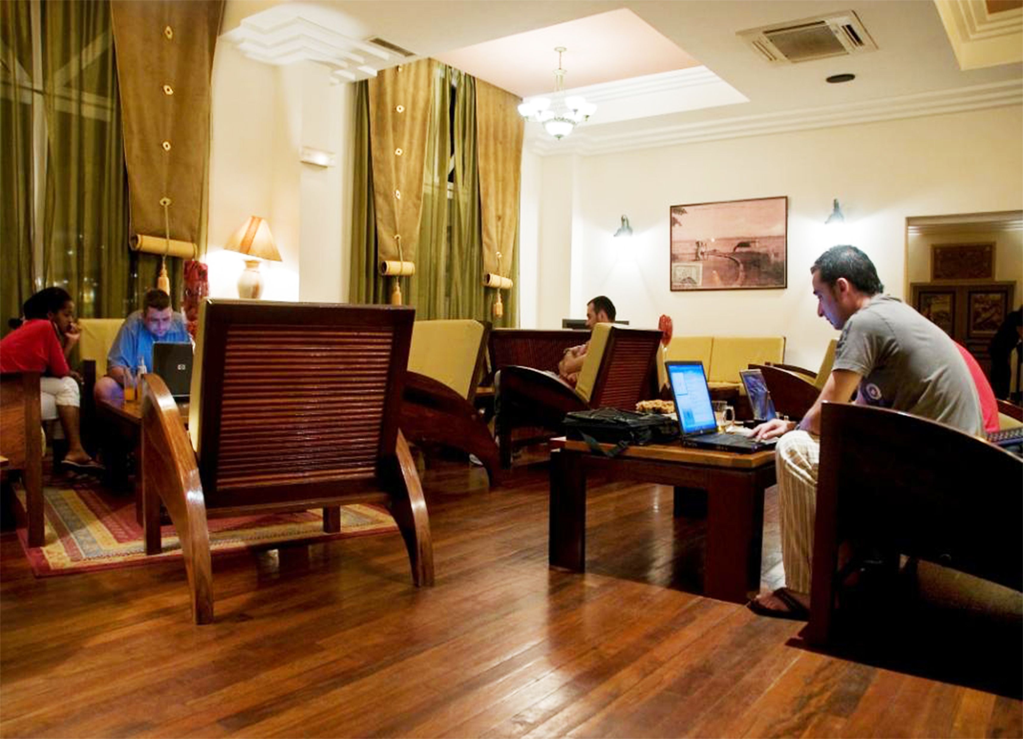 En hotellobby med møbler i træ, en lysekrone og et maleri på væggen.