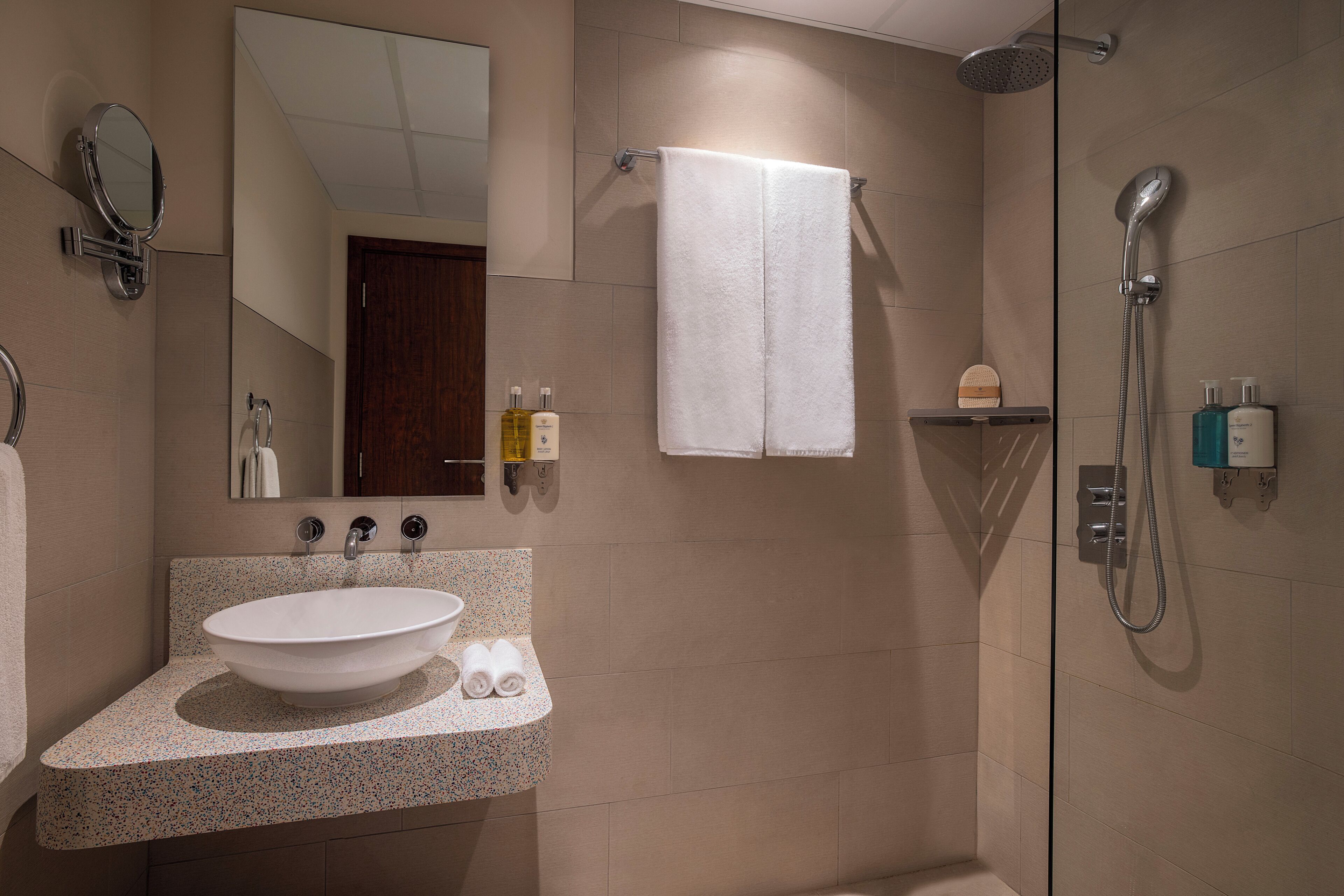A bathroom with a sink, mirror, towel rack, and shower.