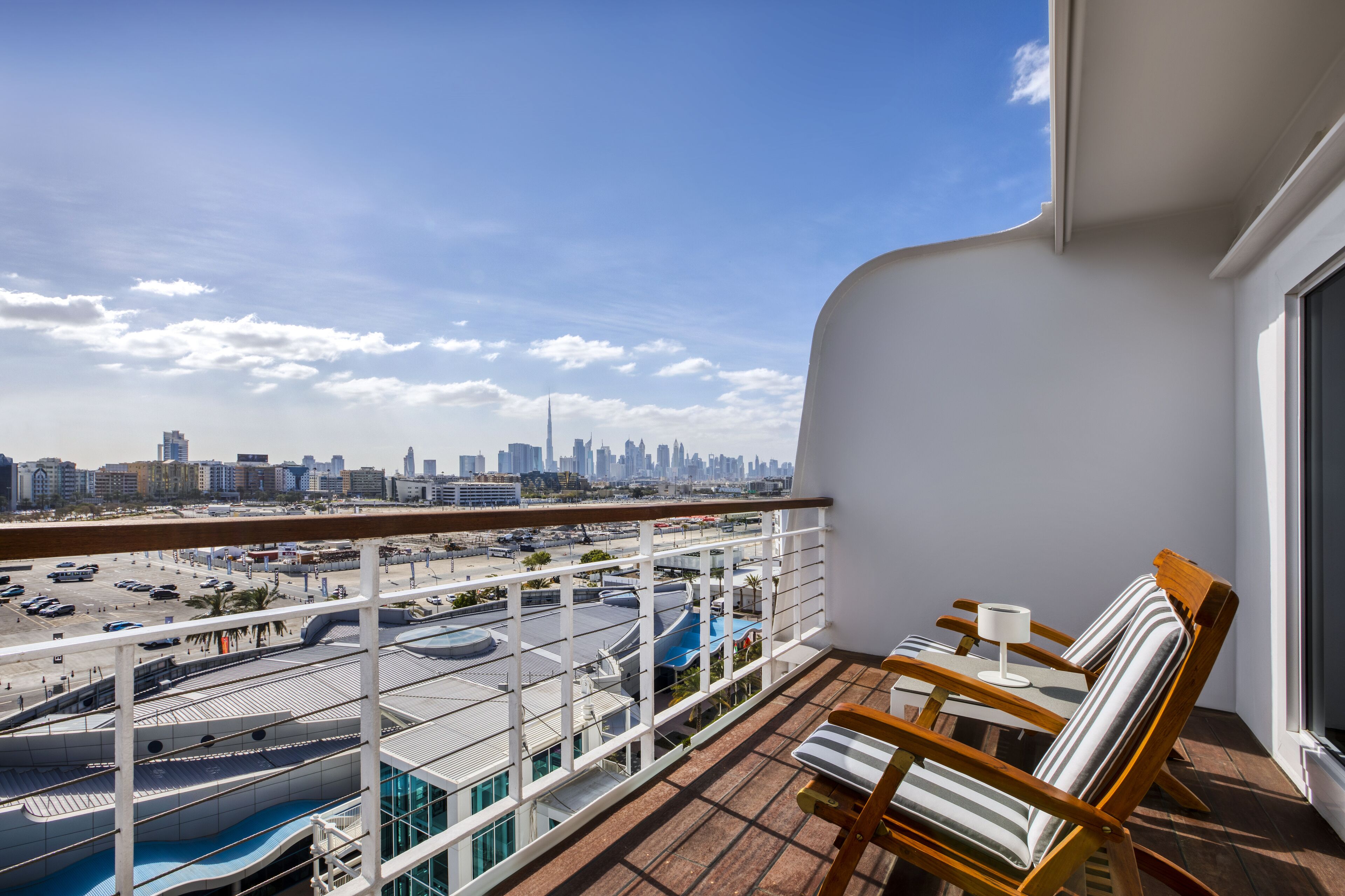 Un balcón con vistas a la ciudad, una piscina y una zona de estar con sillas y una mesa.
