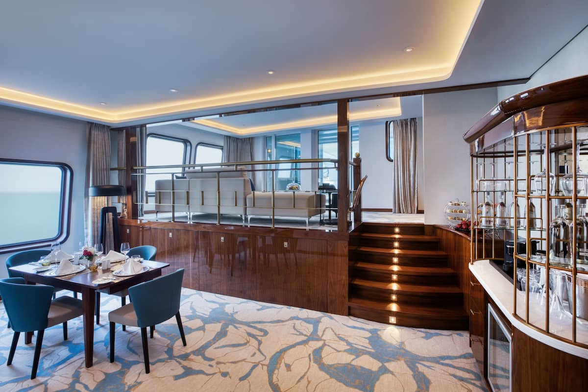A modern interior with a dining area, a staircase, and a bar.