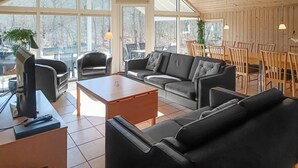 Una sala de estar moderna con un sofá, sillones, una mesa de centro y un televisor.