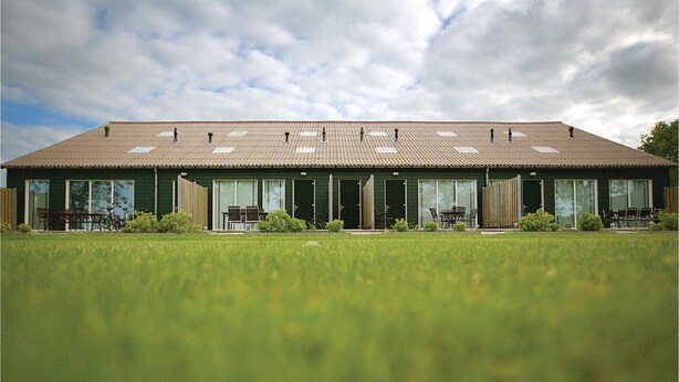 A two-story building with a flat roof, large windows, and a green exterior. - Lovely home in Retranchement with WiFi (Retranchement)