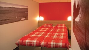 A bedroom with a red wall, a bed with a red and white checkered blanket, and a landscape painting on the wall. - Lovely home in Retranchement with WiFi (Retranchement)
