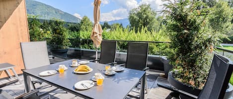 Un área de comedor al aire libre con una mesa para dos, sillas y una planta en maceta.