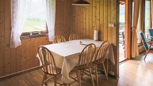 Een houten interieur met een eettafel gedekt voor vier personen, omringd door houten stoelen.