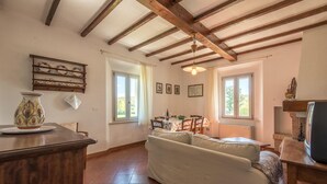Ein gemütliches Wohnzimmer mit Holzboden, einem Essbereich mit Tisch für zwei Personen und einem Sofa.