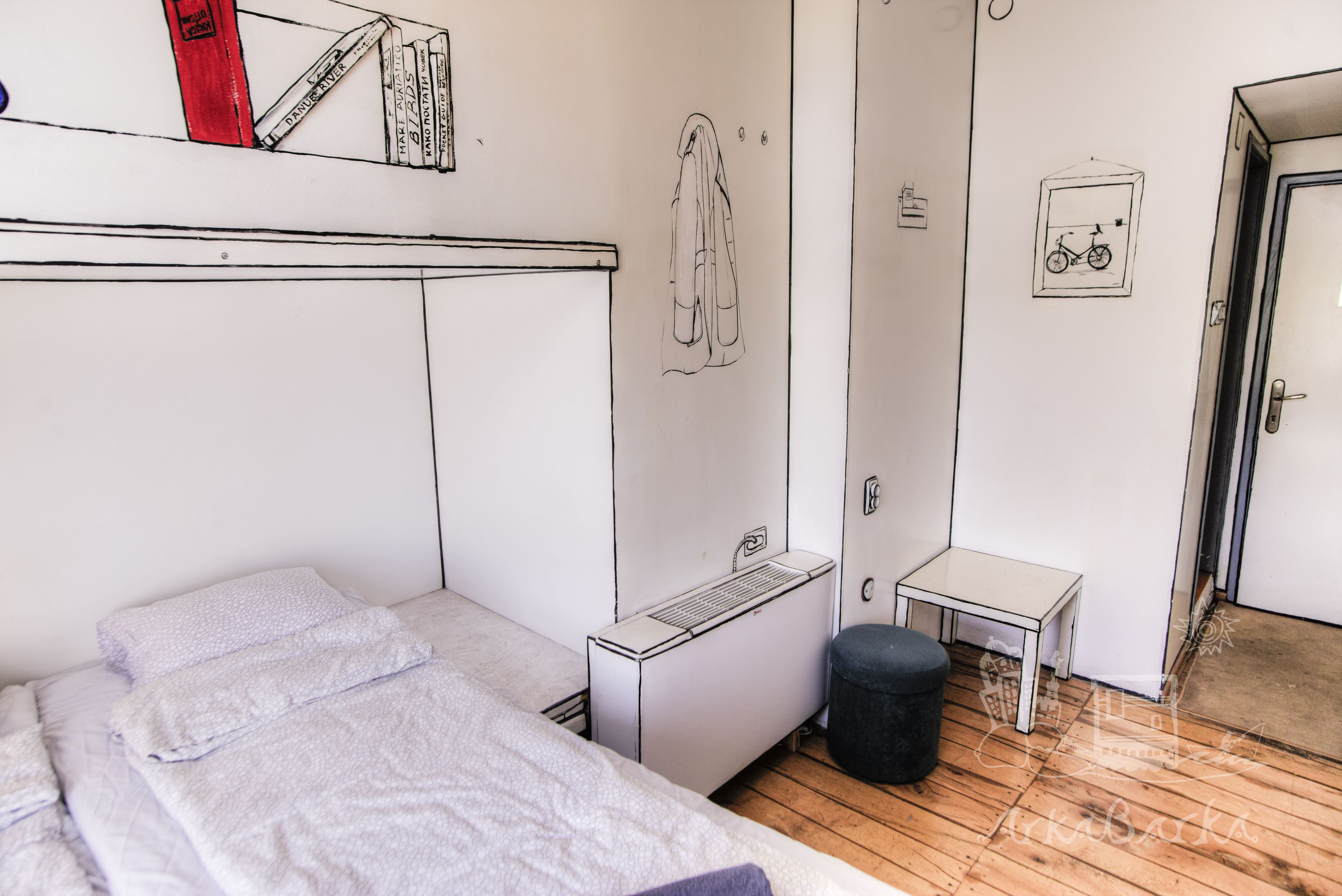 A bedroom with a bed, a radiator, a small table, a stool, and a door.