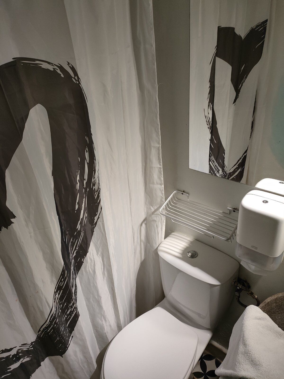 A bathroom with a toilet, a sink with a soap dispenser, and a towel.