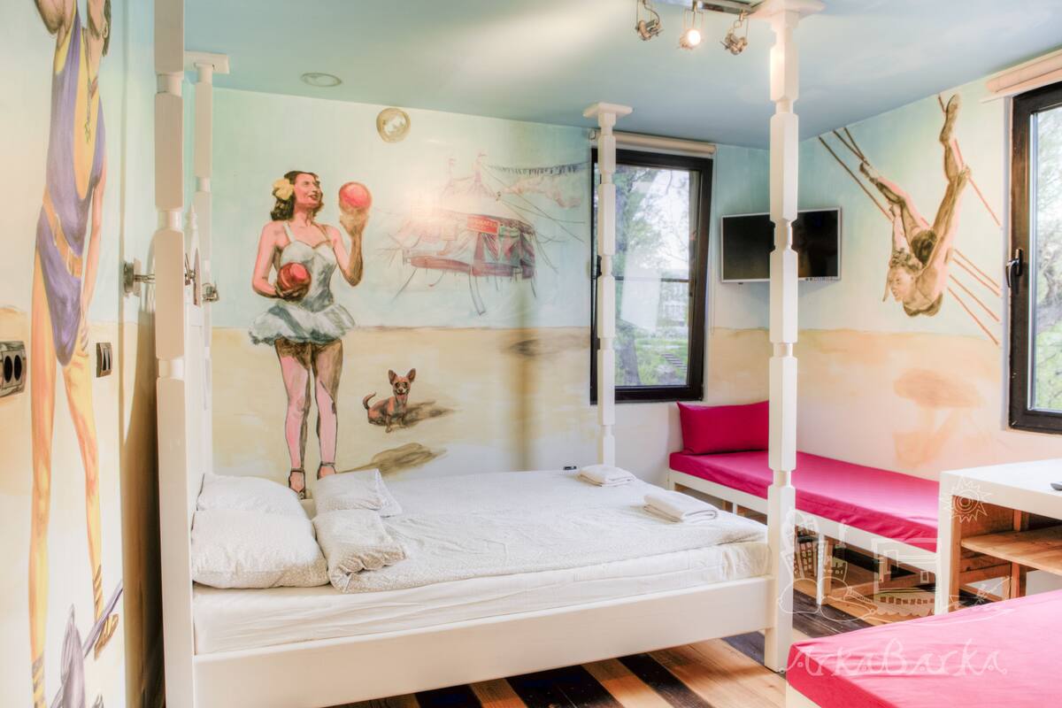 A room with a large bed, a small table, and a window.