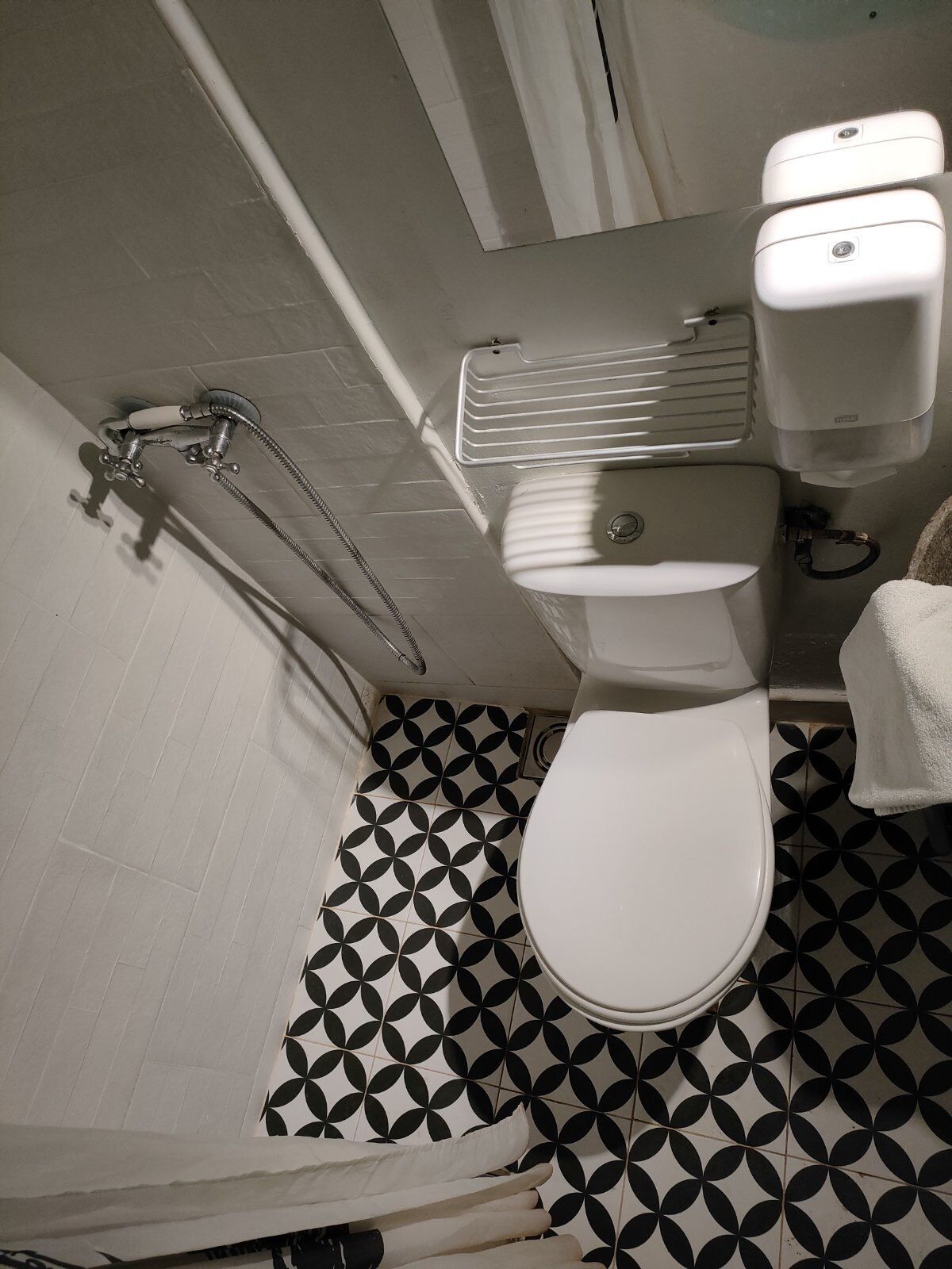 A bathroom with a white toilet, a shower with a chrome faucet, and a toilet paper dispenser.