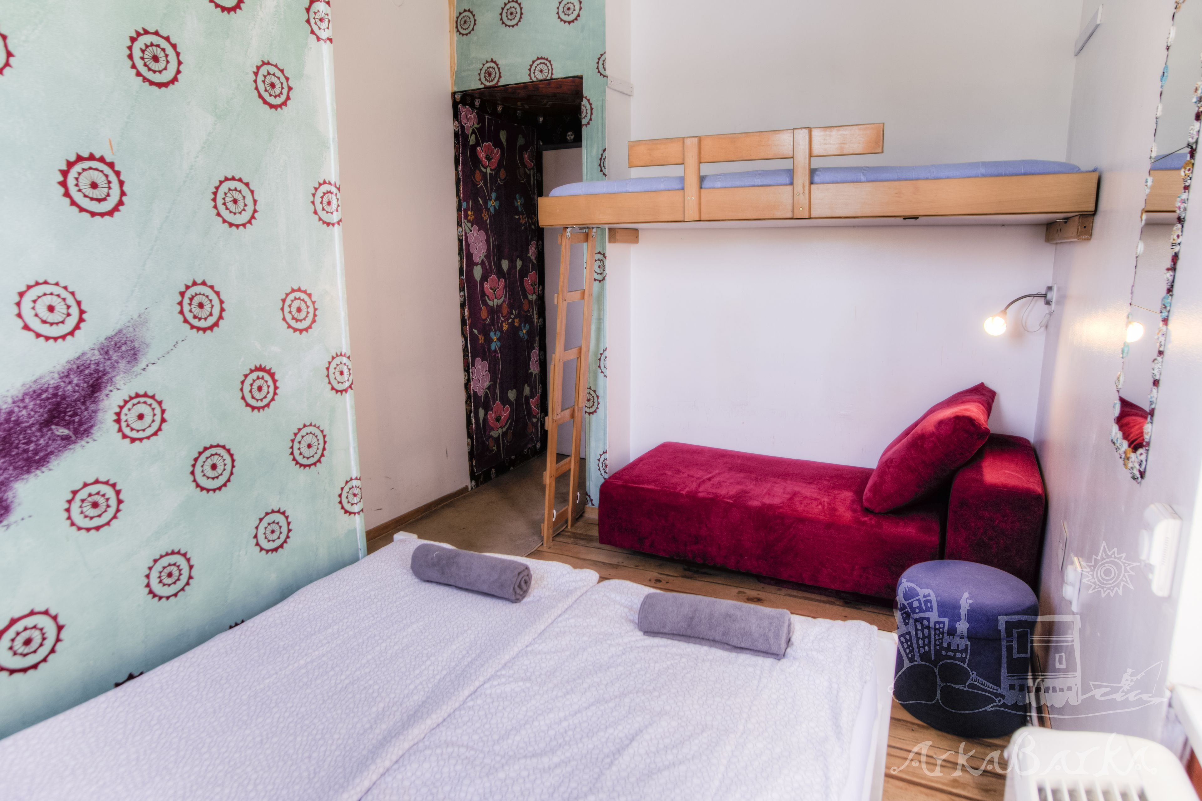 Una habitación con literas, un sofá rojo y una pequeña mesa.