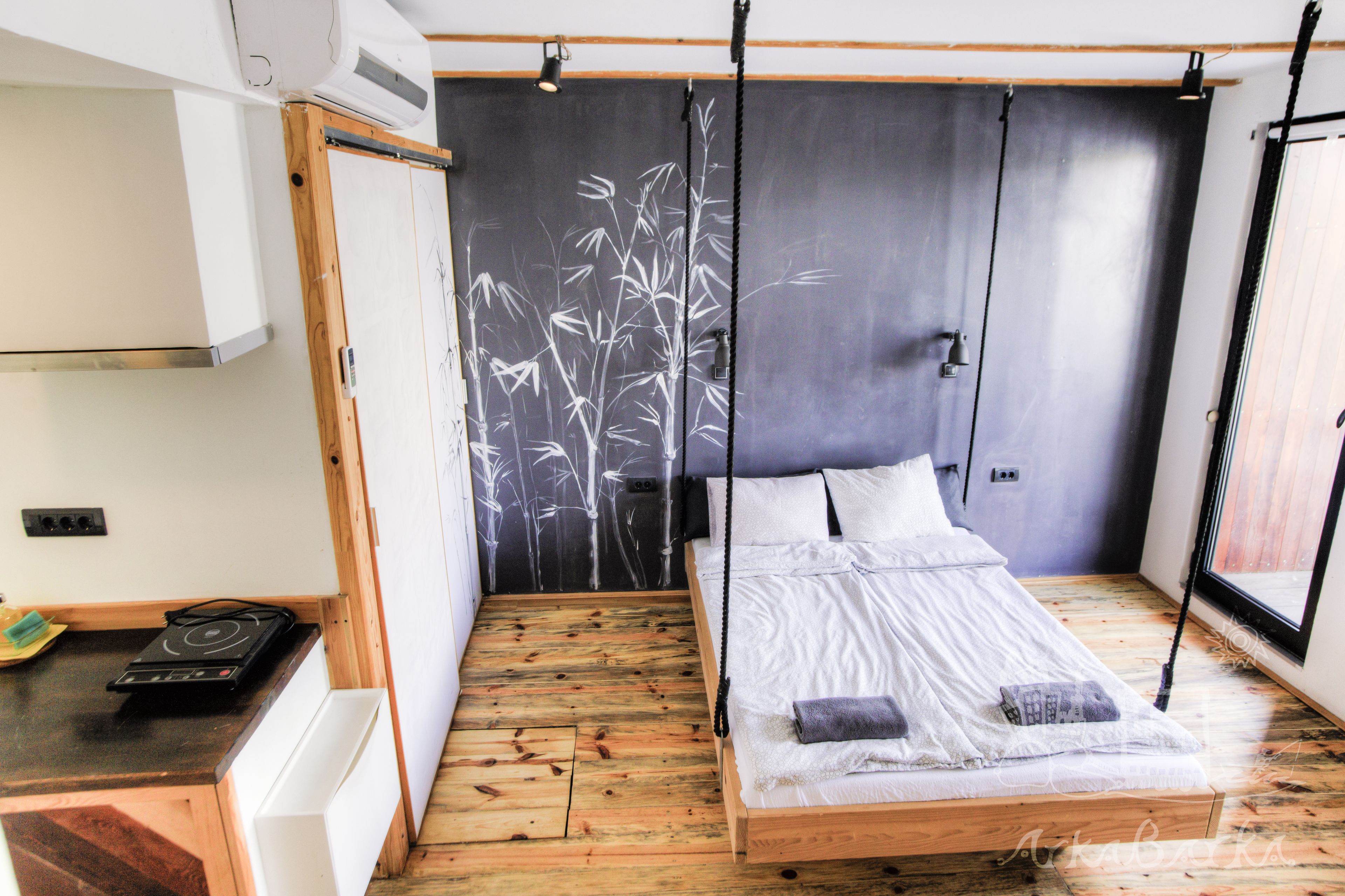 A room with a bed, a small table, and a wall with a bamboo mural.
