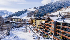 A snow-covered town with modern buildings, a ski slope, and mountains in the background. - SR, Top 9 - Ap. 87m² mit 2 SZ, Balkon 18m² (Zell am See)