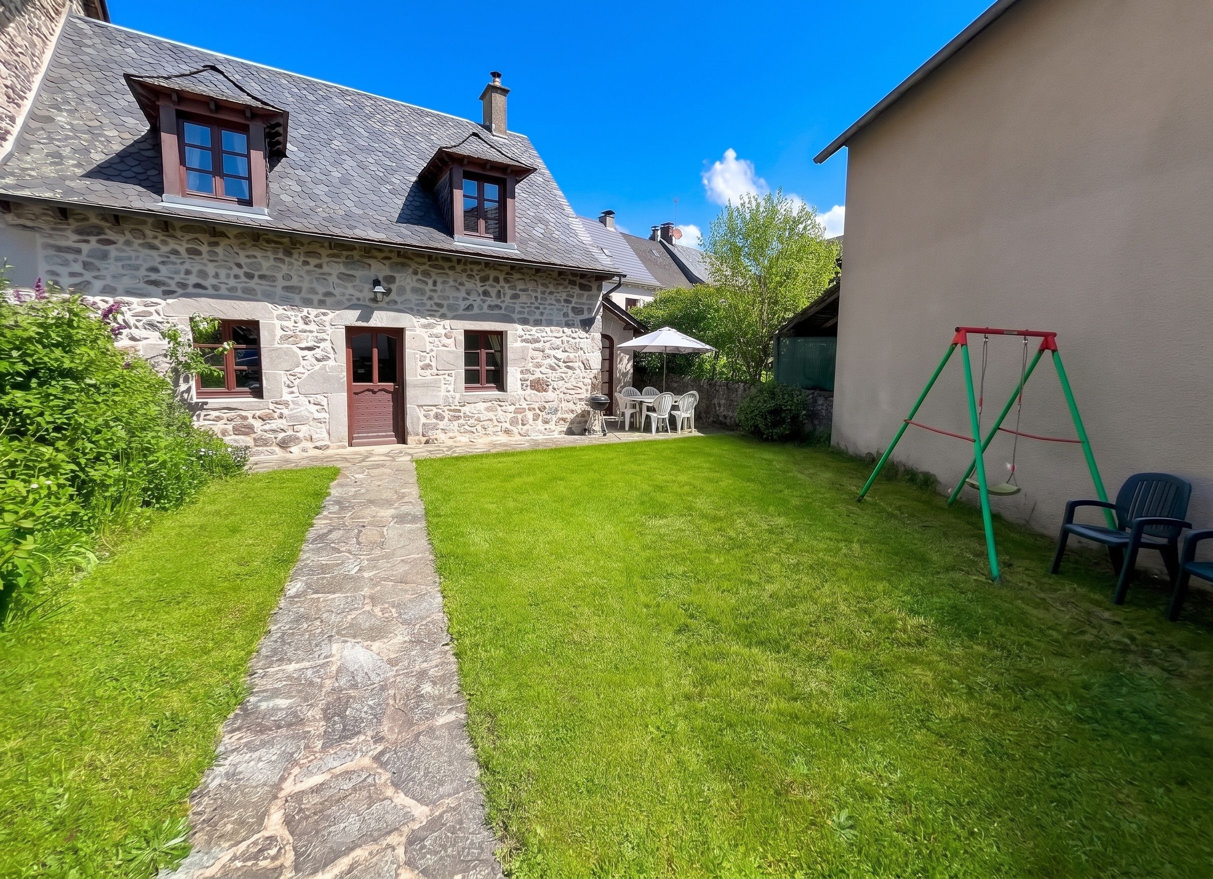 Une maison en pierre avec un chemin de pierre menant à une cour gazonnée.