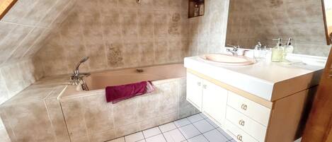 A bathroom with a bathtub, a sink, and a mirror.