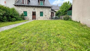 A stone house with a grassy yard, a wooden door, and a chimney. - Homerez - Charming House in Lanobre with Garden (Lanobre)