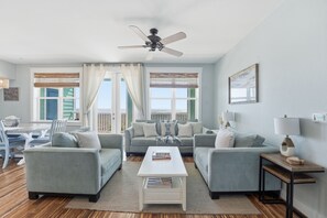 A modern living room with two sofas, a coffee table, and a ceiling fan.