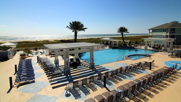 A resort pool area with sun loungers, a covered seating area, and a view of the beach. - Knot 4 Sail -Beach Front- Ocean Views- Front Row - 2BD/2BA. Sleeps 6 (Galveston)