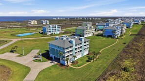A coastal residential area with multiple two-story buildings, a clear sky, and a view of the ocean.